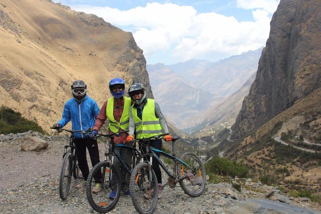 Ciclistas en un abra con quebradas y cumbres al fondo