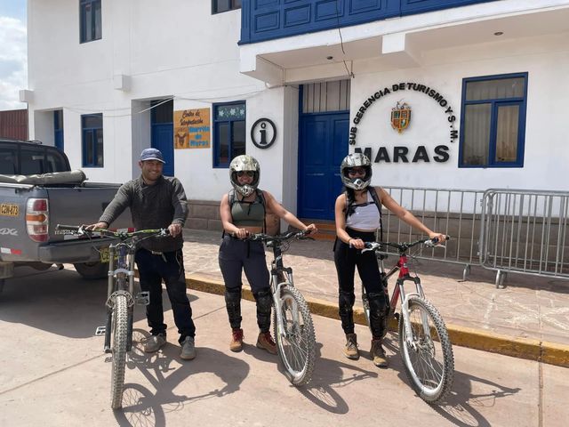 Tres ciclistas con sus bicicletas frente a la municipalidad de Maras