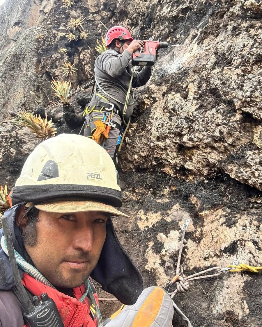 Sota Adventure guide in a helmet fitting safety anchors on the rock face