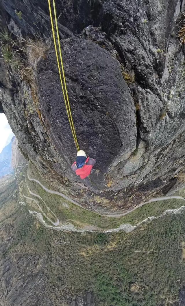 Escalador descendiendo en rápel por una pared vertical sobre el valle