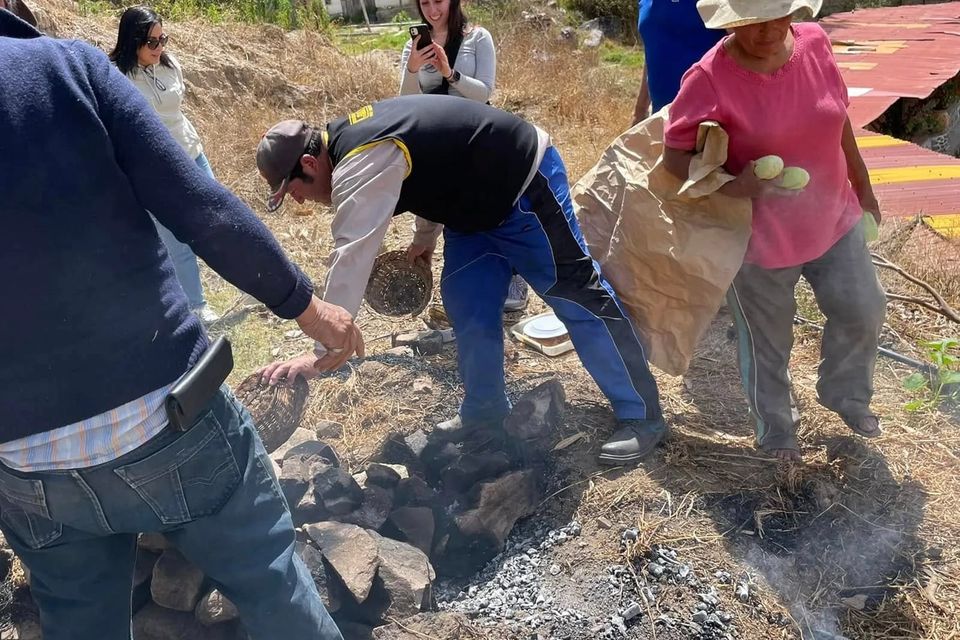 Viajeros preparando la pachamanca con piedras calientes en el campamento