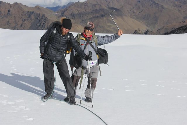 Guía y viajero caminando sobre la nieve de un nevado andino