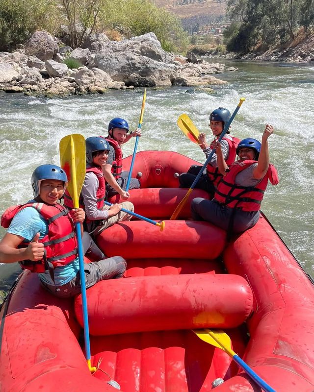 Group with helmets and paddles celebrating in a red raft