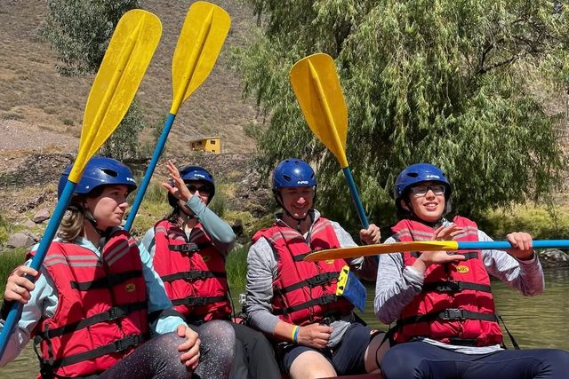 Cuatro viajeros con casco, chaleco y remos listos para el rafting