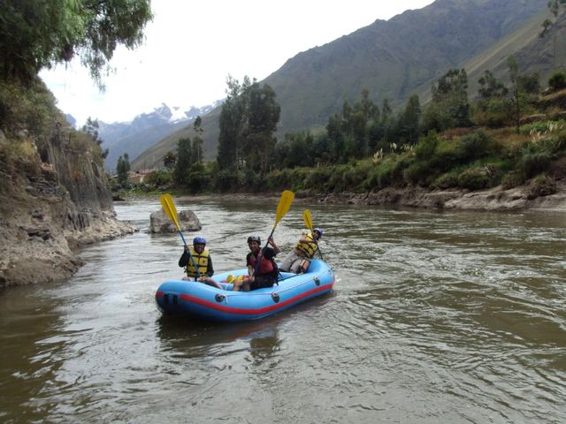 Blue raft paddling a calm stretch surrounded by mountains