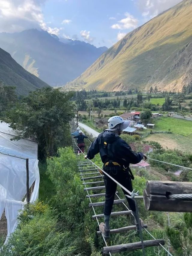 Traveller in a harness crossing a cable bridge overlooking the valley